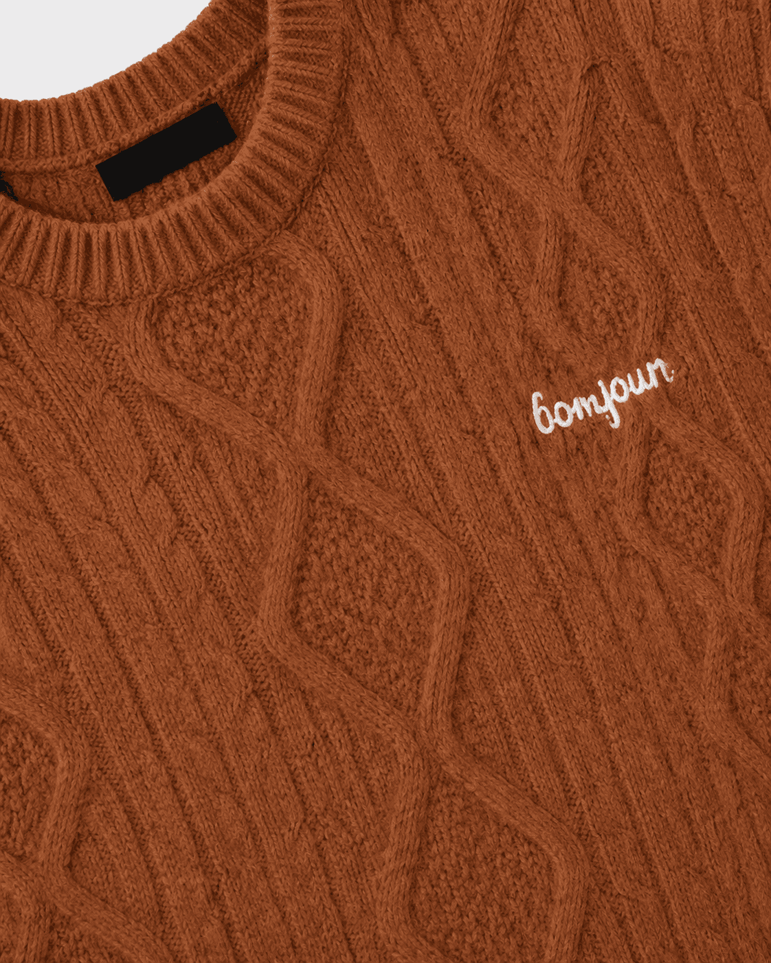Brown cable knit sweater with 'bonjour' embroidery on a light gray background