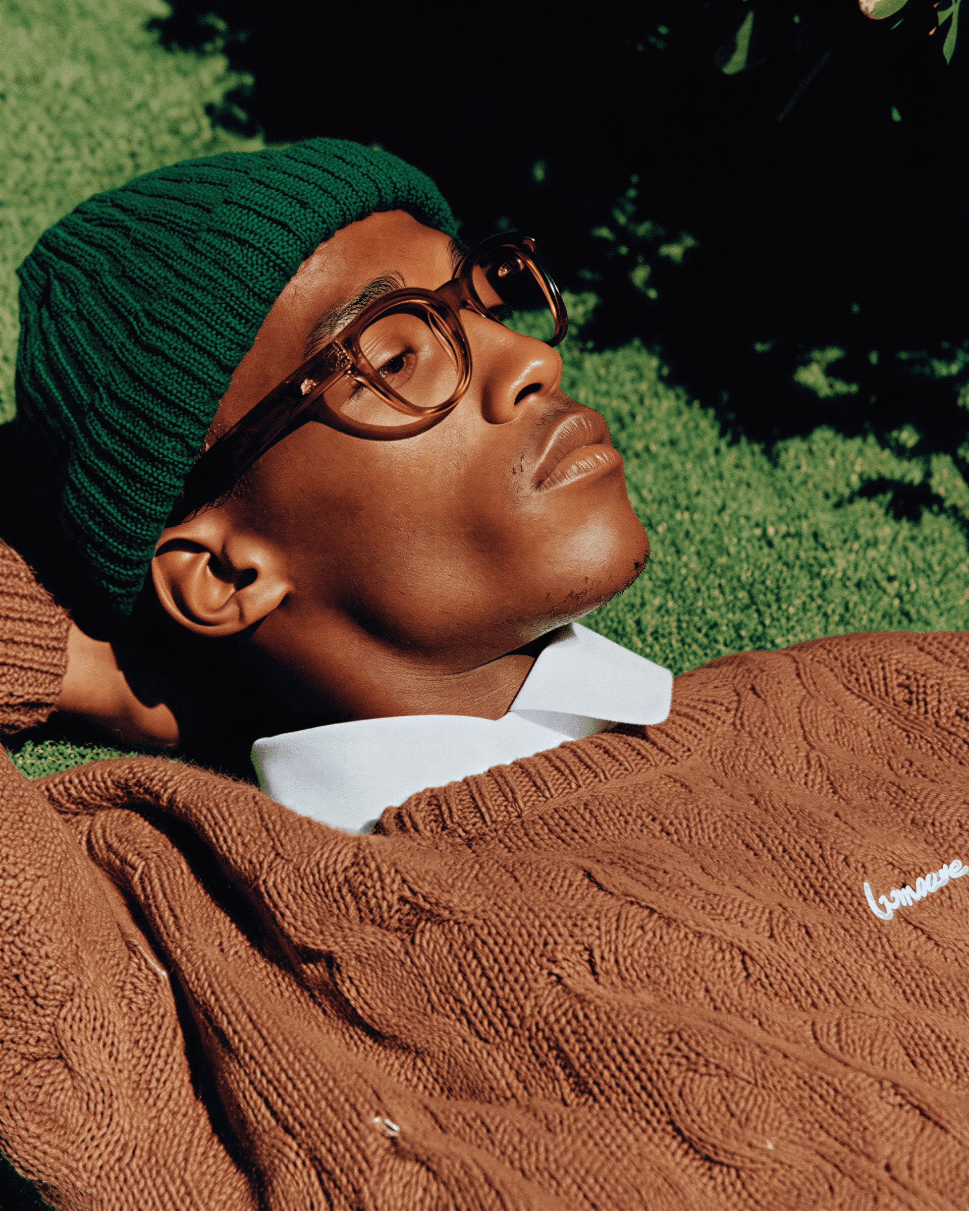 Person wearing a green beanie and brown sweater with a blurred background