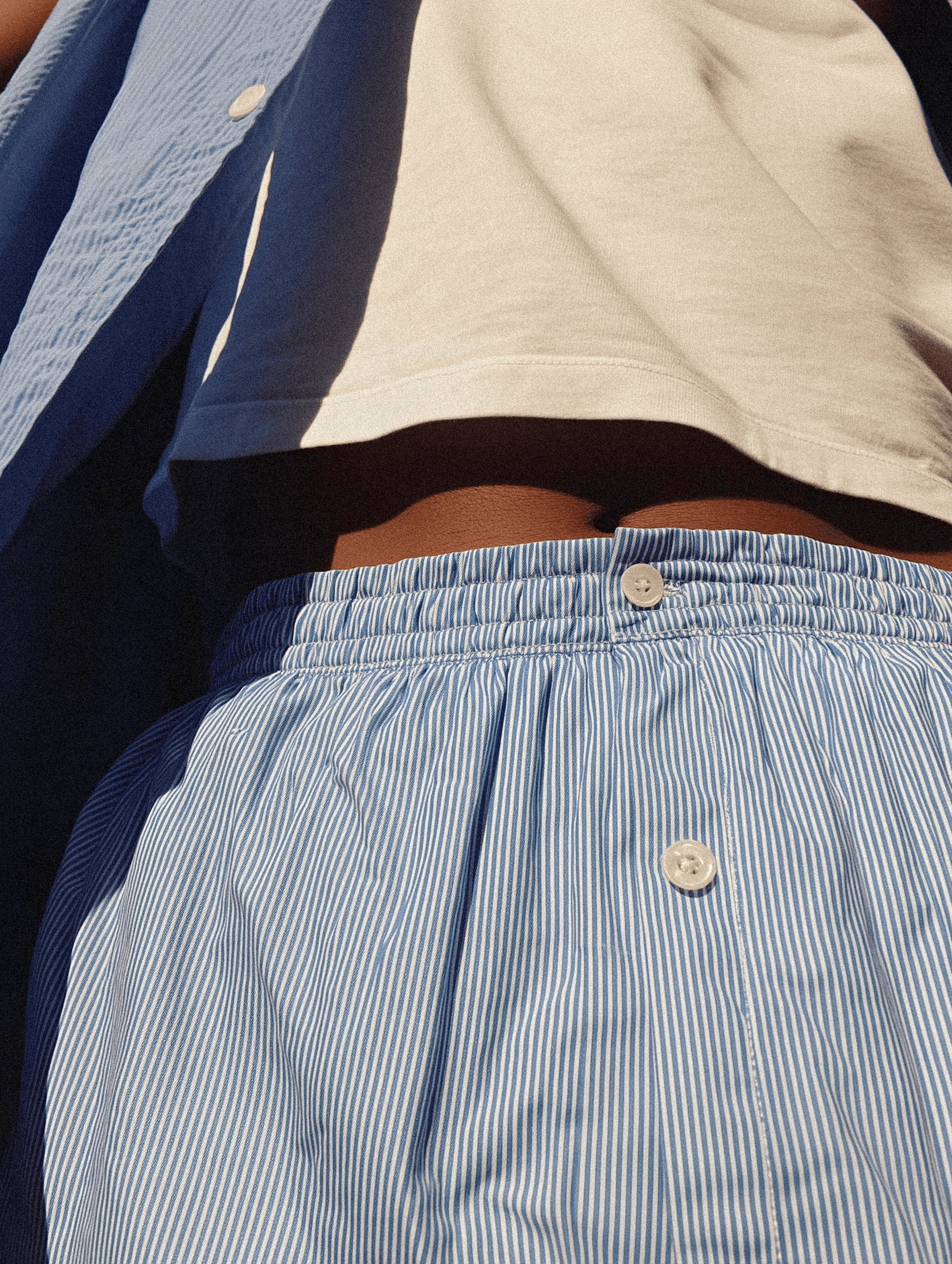 Close-up of a person wearing a blue and white striped shirt with buttons.