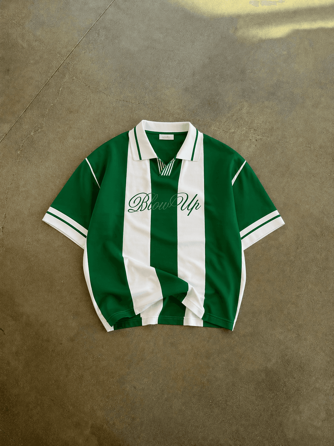 Green and white striped shirt with 'Blessed Up' text on a brown surface
